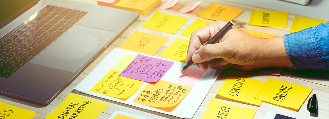 Persona Organizando su Estrategia de Marketing en Post-Its de Colores Sobre Escritorio