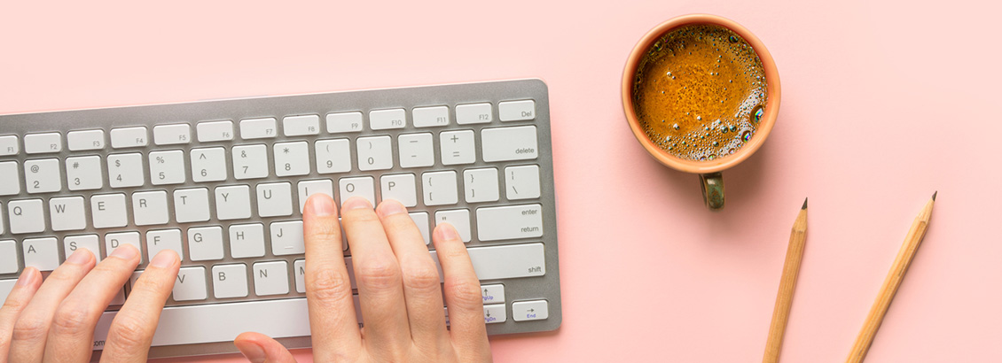 Persona Escribiendo Post de Redes en Teclado Junto a su Taza de Café