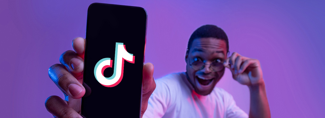 Chico Emocionado Mostrando a la Cámara la Pantalla de su Teléfono con Logo de TikTok Dentro