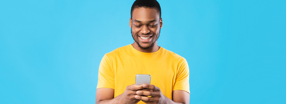 Hombre Joven Sonriente que Sostiene su Smartphone