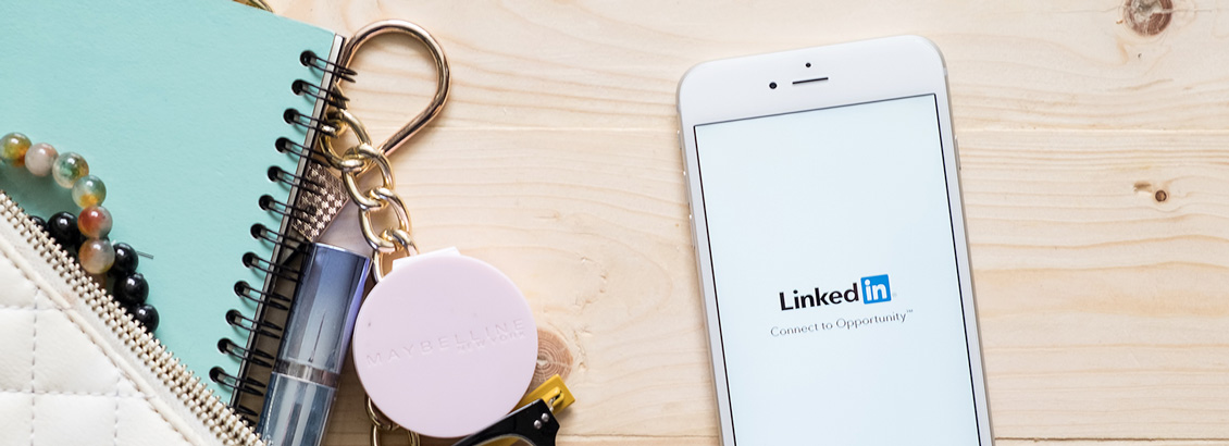 Smarthpone Sobre Escritorio de Madera con Logo de LinkedIn en Pantalla