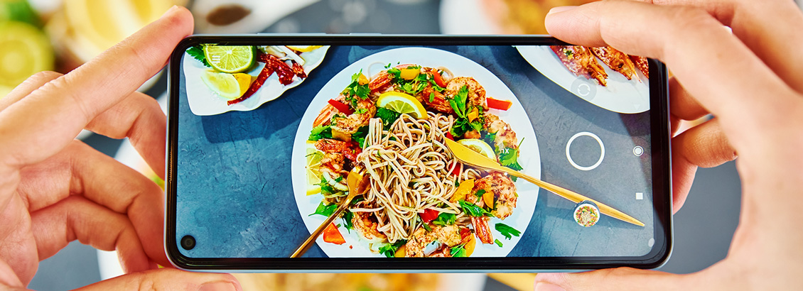 Persona Tomando Foto de Plato en su Telfono Para Actualizar su Feed en Redes