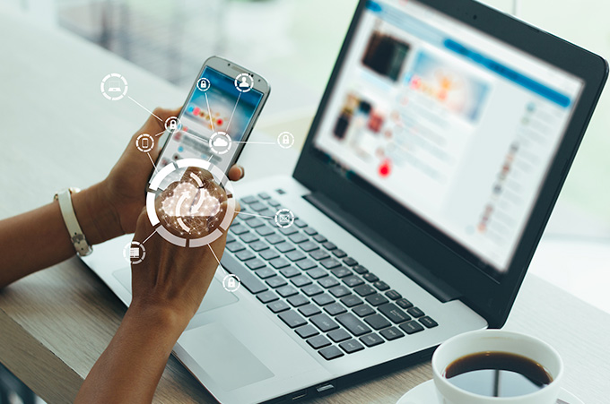 Persona Accesando a Redes Sociales desde Smartphone y Laptop