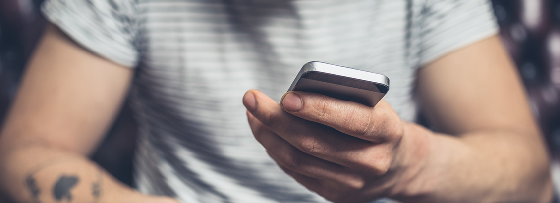 Plano Cercano del Torso de un Hombre que Sostiene su Smartphone