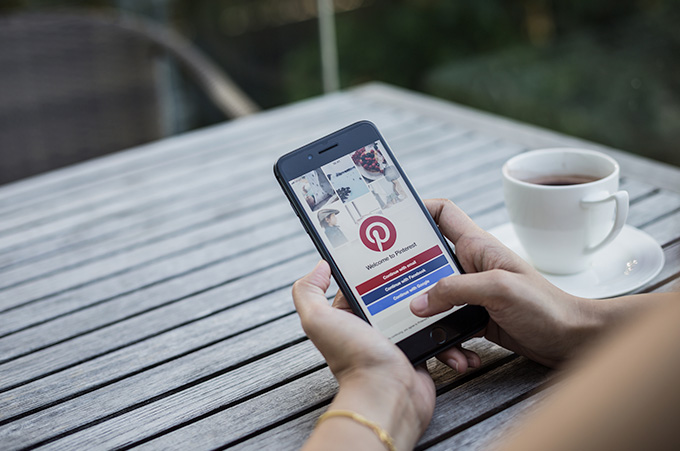 Persona Sentada en Cafetera Sosteniendo su Telfono Mientras Hace Bsqueda en Pinterest