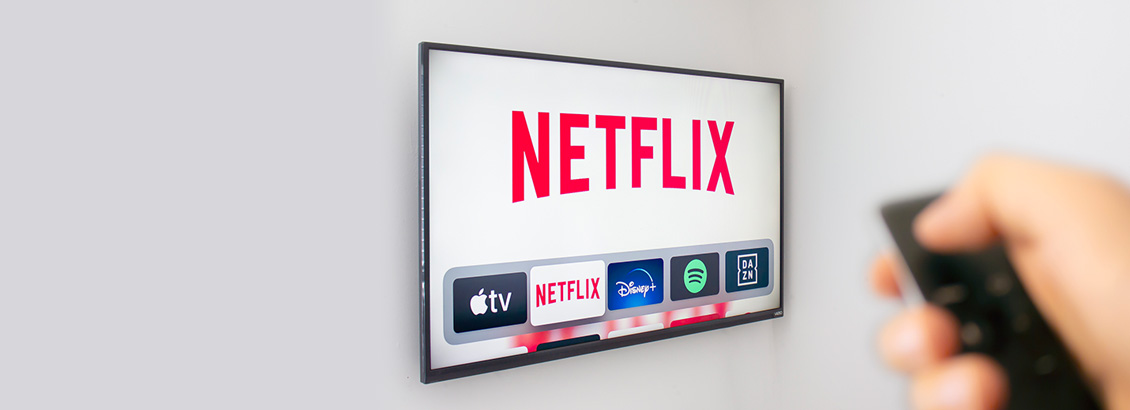 Mano Sosteniendo Control Frente a Pantalla de TV con Netflix