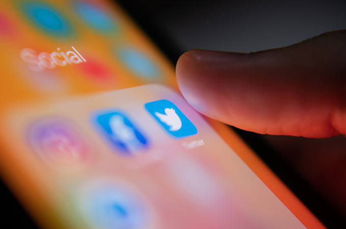 Dedo Pulsando cono de Twitter en Pantalla de Smartphone