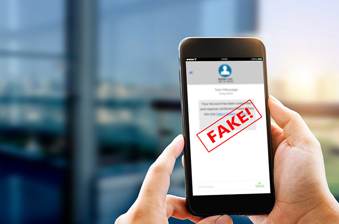 Manos Sostienen Smartphone que dice FAKE en su Pantalla