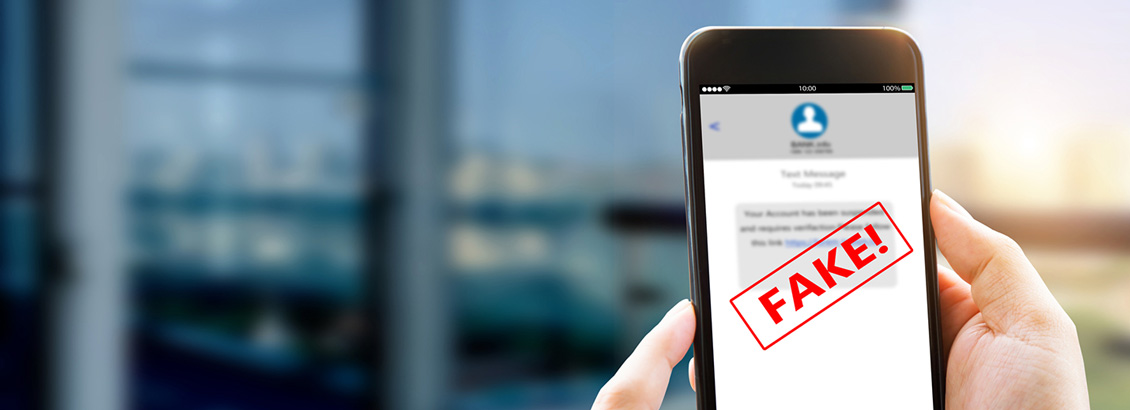 Manos Sostienen Smartphone que dice FAKE en su Pantalla