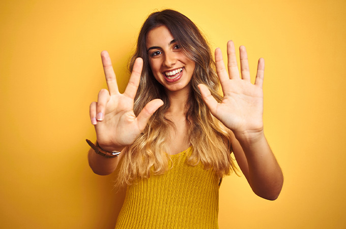 Mujer Joven y Sonriente Mostrando Ocho Dedos de su Manos