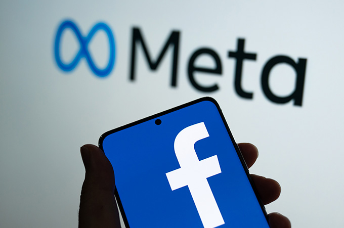 Mano Sosteniendo Smartphone con el Logo de Facebook y Logo de Metaverso Detrs