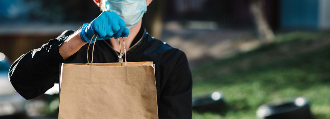 Chico de Delivery con Tapabocas y Guantes Sosteniendo Bolsa con Pedido a Entregar