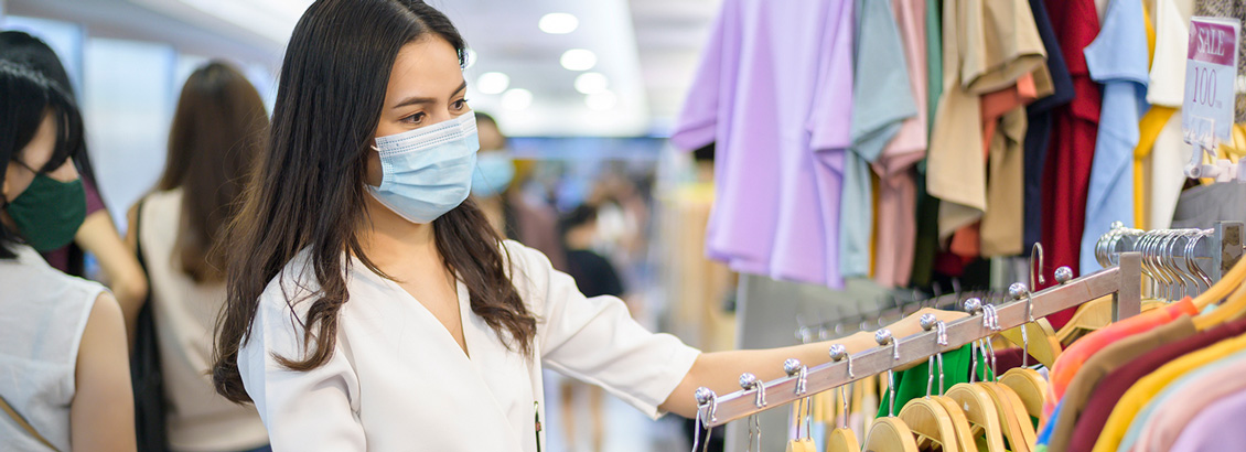Consumidora con Tapabocas Comprando Ropa en Tienda Luego de Pandemia