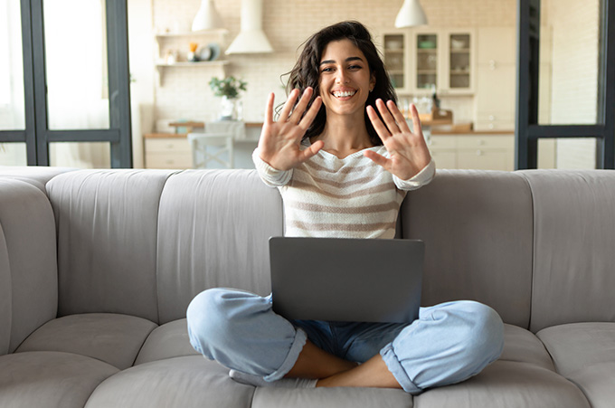 Mujer Sonriente Sentada en Sof Extendiendo Sus Manos Hacia el Frente