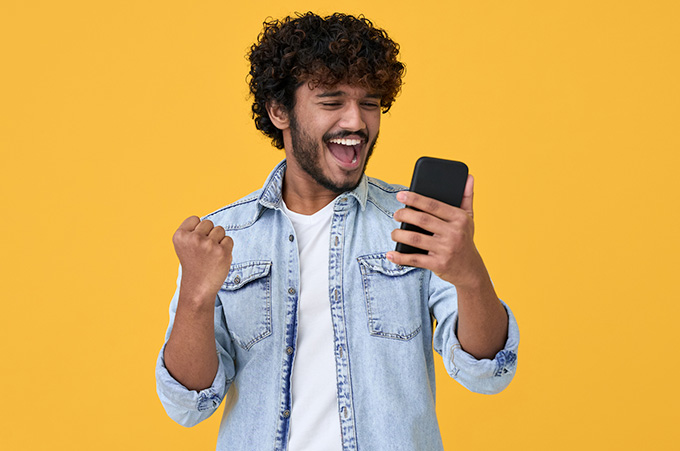 Hombre Joven con Gesto de Celebracin Mientras Revisa su Telfono
