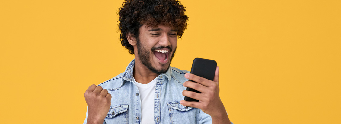 Hombre Joven con Gesto de Celebracin Mientras Revisa su Telfono