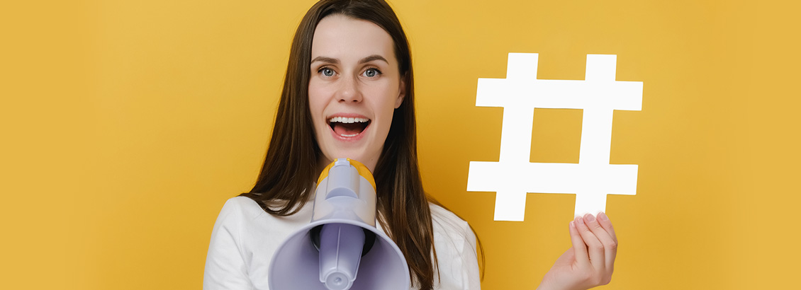 Chica Influencer Sosteniendo una Figura de Hashtag con una Mano y Megfono con Otra