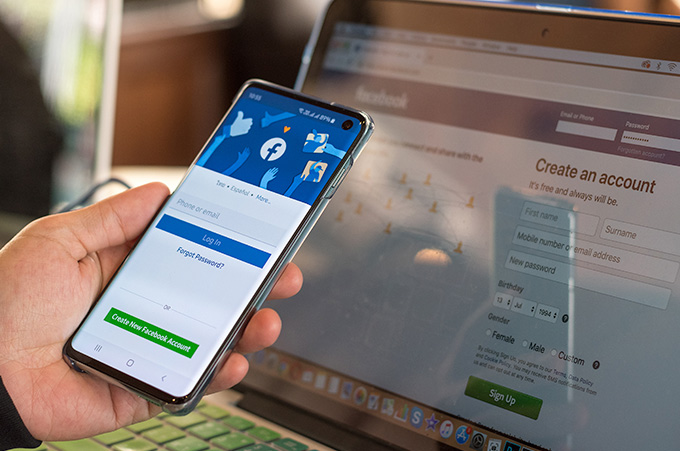 Persona con Facebook Abierto en su Smartphone y en su Laptop