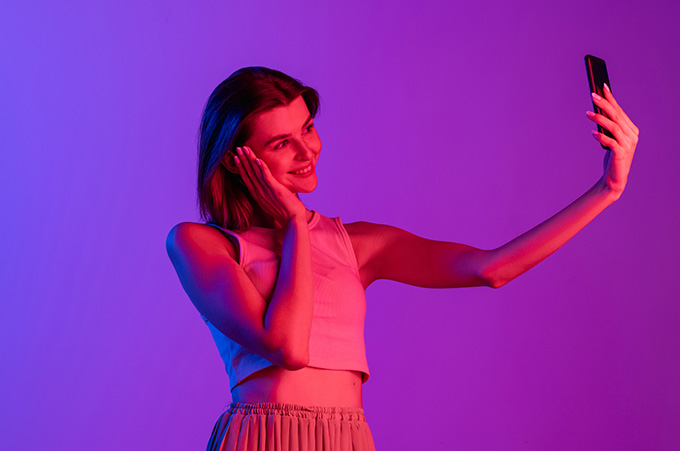 Chica Influencer Bajo Luces de Nen Mientras Toma Selfie con Smartphone