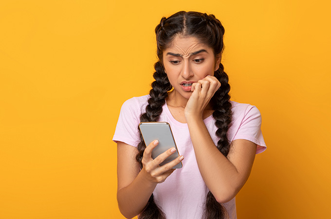 Chica Mirando su Smartphone con Expresin Preocupada ya que sus Videos y Fotos Fueron Borradas