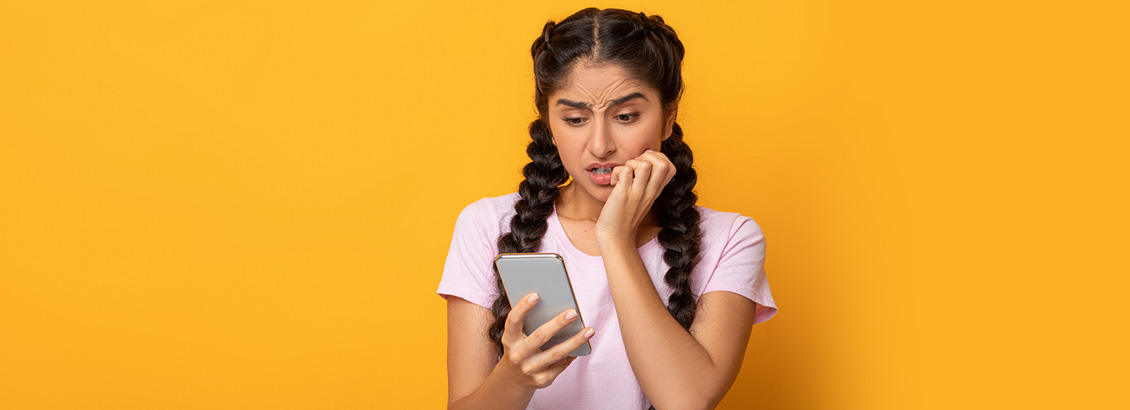 Chica Mirando su Smartphone con Expresin Preocupada ya que sus Videos y Fotos Fueron Borradas