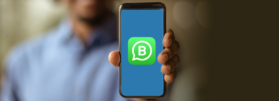 Dueño de Negocio Sosteniendo Smartphone con Logo de WhatsApp Business Dentro