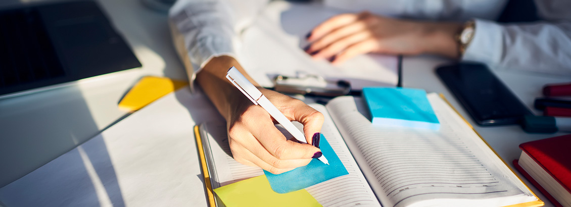 Persona Escribiendo su Libro en Bloc de Notas Abierto con Notas Adhesivas