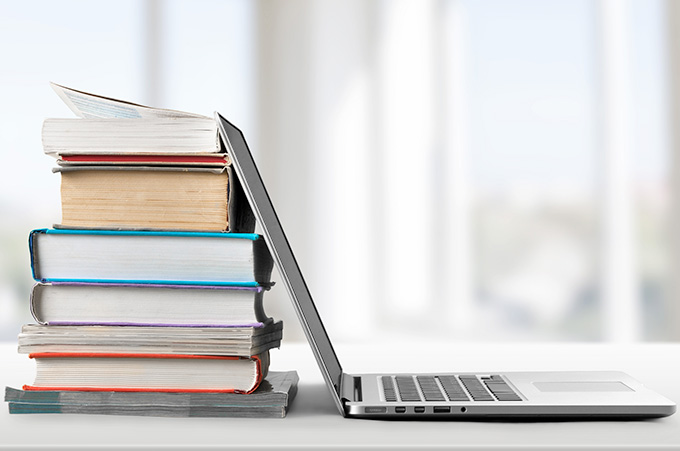 Pila de Libros Apoyados Sobre Laptop Abierta