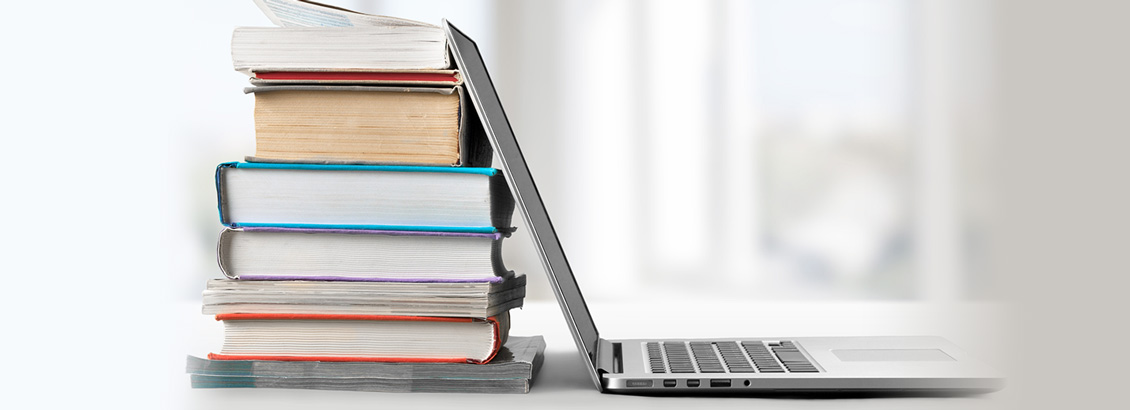 Pila de Libros Apoyados Sobre Laptop Abierta