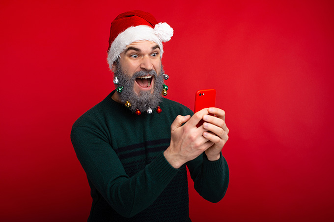Influencer con Gorro y Adornos Navideos en el Rostro Mientras Graba en su Smartphone