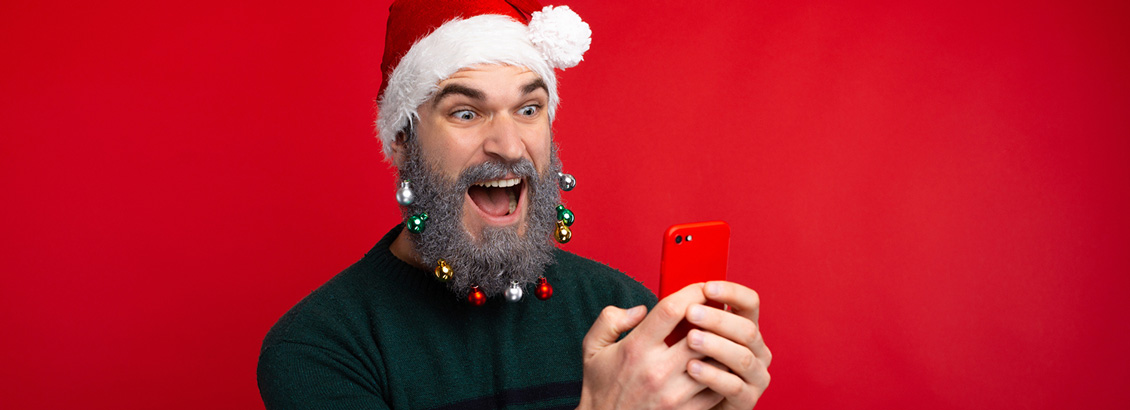 Influencer con Gorro y Adornos Navideños en el Rostro Mientras Graba en su Smartphone