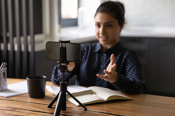Chica Empresaria Sentada Frente a Smartphone Grabando Mientras Lee Teleprompter