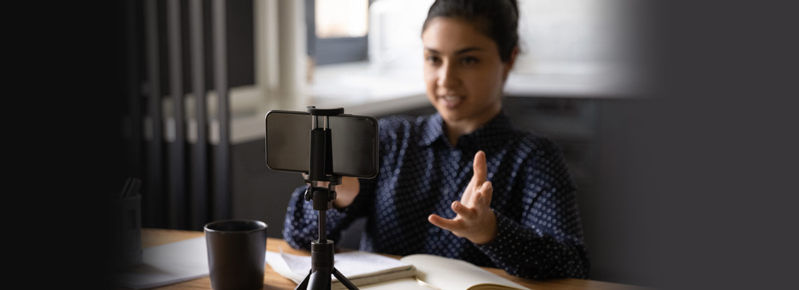 Chica Empresaria Sentada Frente a Smartphone Grabando Mientras Lee Teleprompter