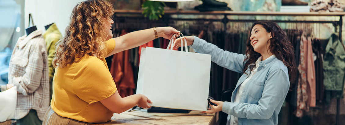 Vendedora Entregando Bolsa a Compradora en Tienda Física