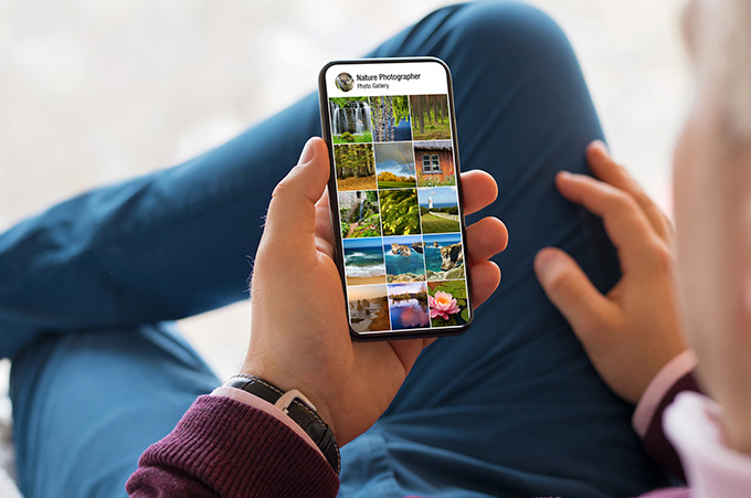Hombre que Revisa, Desde su Smartphone, un Perfil Lleno de Paisajes Naturales