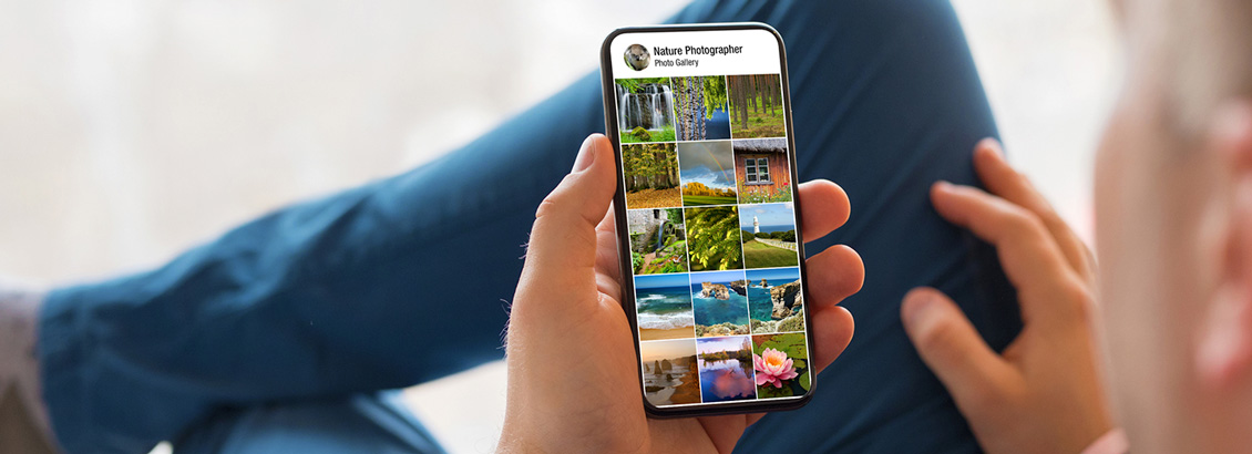 Hombre que Revisa, Desde su Smartphone, un Perfil Lleno de Paisajes Naturales