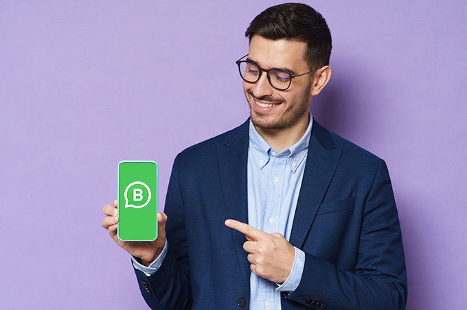 Empresario Apuntando a Smartphone con Logo de WhatsApp Business en Pantalla
