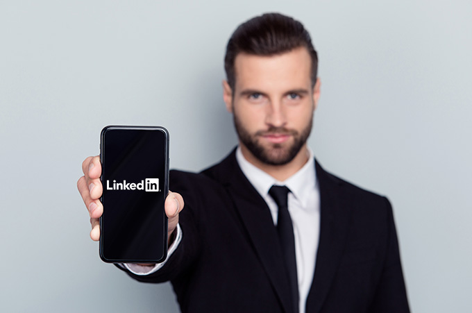 Empresario Mostrando Smartphone a la Cmara con Logo de LinkedIn en Pantalla