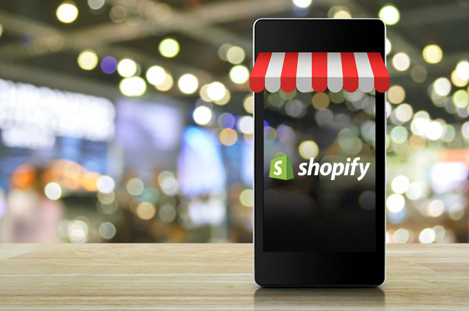 Smartphone con Accesorios de Tienda y el Logo de Shopify en la Pantalla