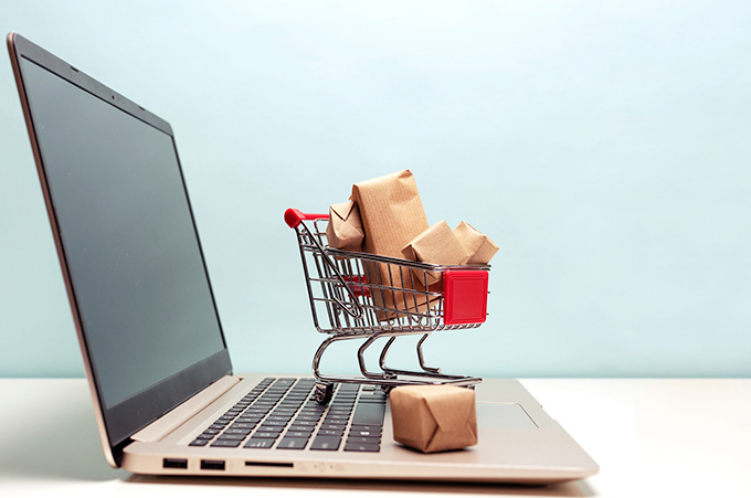 Laptop Abierta con Ornamento en Forma de Carrito de Compras Lleno Sobre Teclado