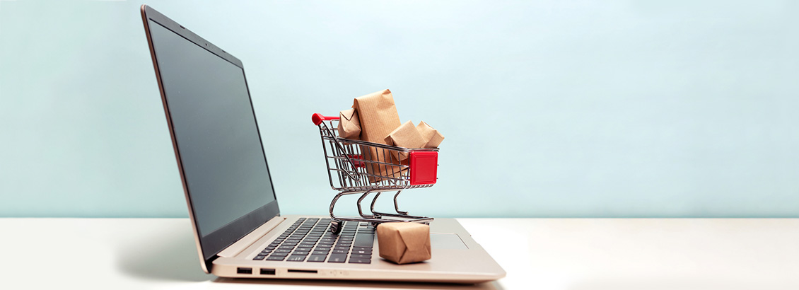 Laptop Abierta con Ornamento en Forma de Carrito de Compras Lleno Sobre Teclado