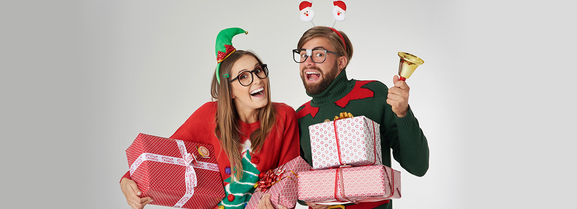 Pareja Geek Vestida con Sweaters Navideños y Sosteniendo Regalos
