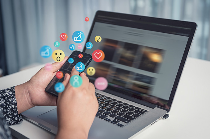 Persona con Telfono en Mano y Laptop, Gestionando sus Redes Sociales
