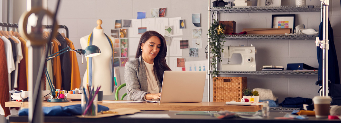 Emprendedora en su Taller de Modas Sentada Frente a Laptop