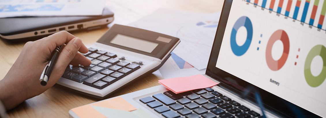 Mano Usando Calculadora Junto a Laptop Mostrando Gráficas de Negocios