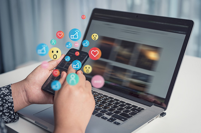 Mano Sosteniendo Telfono con Distintos Emojis Sobresaliendo de l