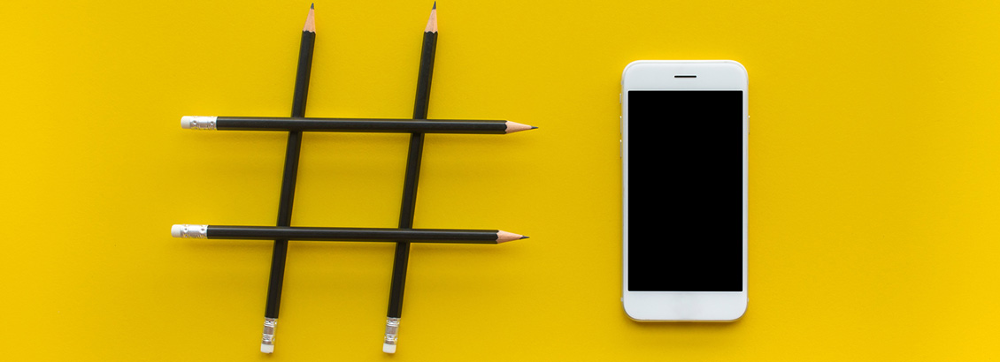 Imagen con Fondo Amarillo, un Signo de Hashtag con Lápices y un Smartphone