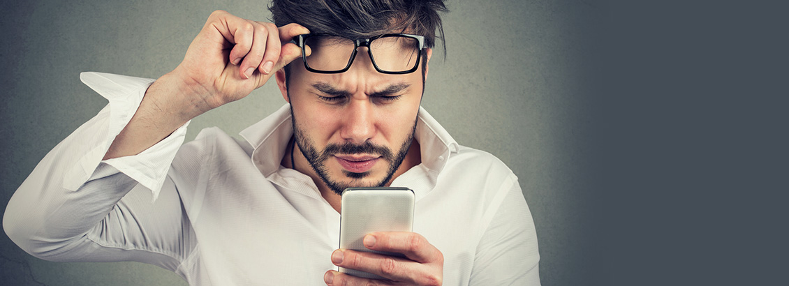 Hombre con Lentes en su Frente y con Dificutad Para Leer en su Smartphone