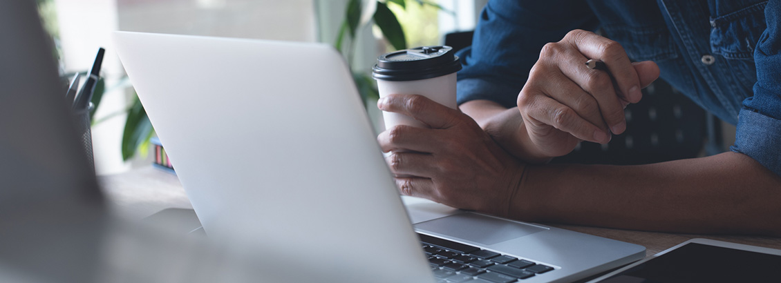 Hombre Sosteniendo Envase de Caf y Revisando Redes Sociales desde Laptop