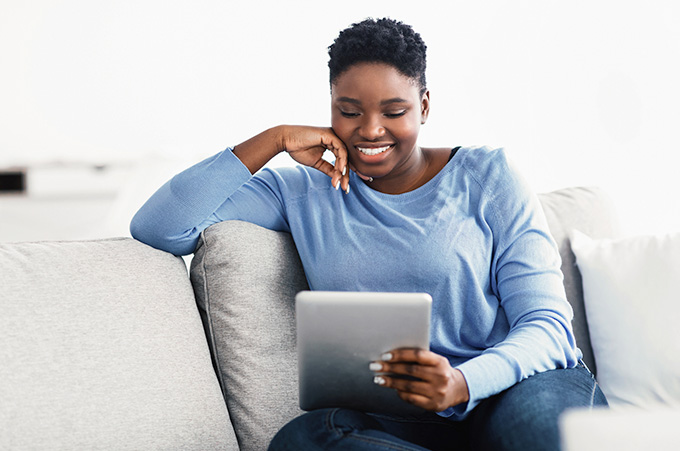 Mujer Sentada en Sof Revisando Redes Sociales desde Tablet sin Afectar su Salud Mental